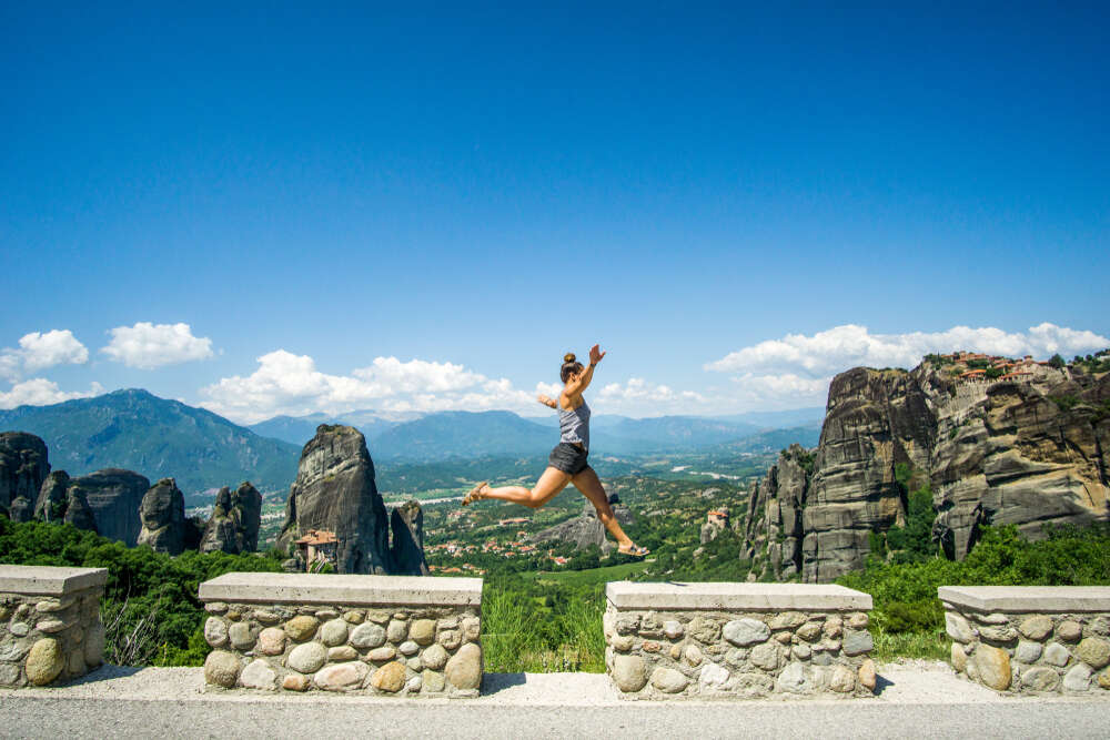 A girl jumping in front of mountainous
